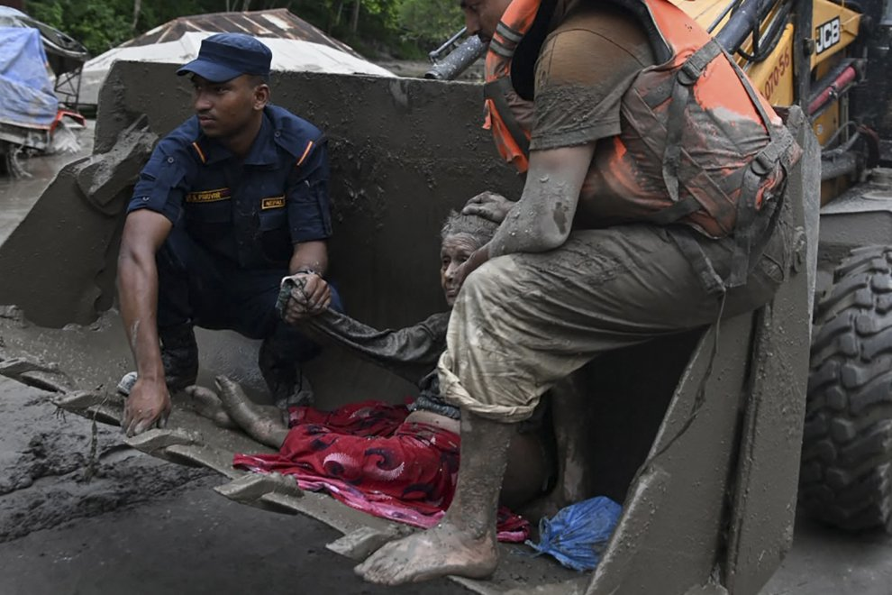 Rescue workers assist a person after severe flooding in Nepal.
