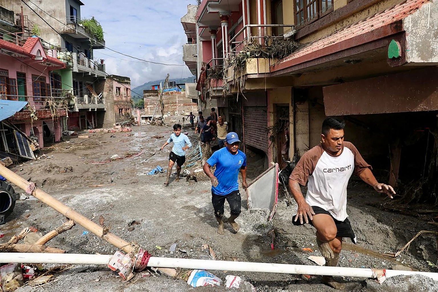 People move through a flood-damaged neighborhood in Nepal.