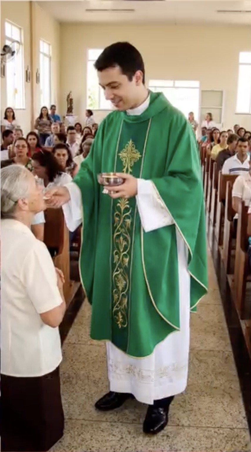 Father Miguel before the amputations, standing and giving Communion